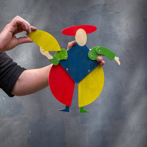 Hands posing the colorful Bauhaus harlequin puppet, adjusting its movable arms by hand