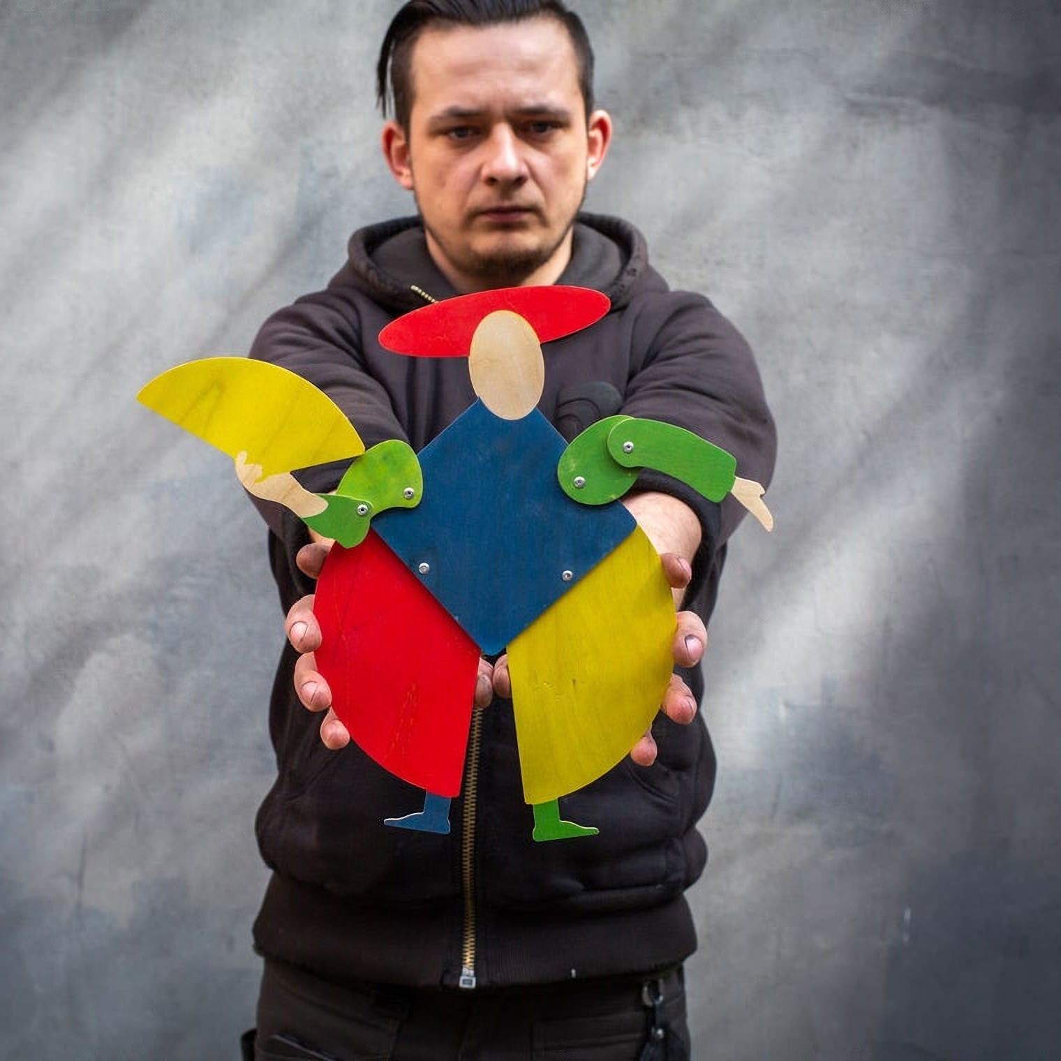Maker holding Bauhaus harlequin wooden puppet in both hands to show scale — 38 cm