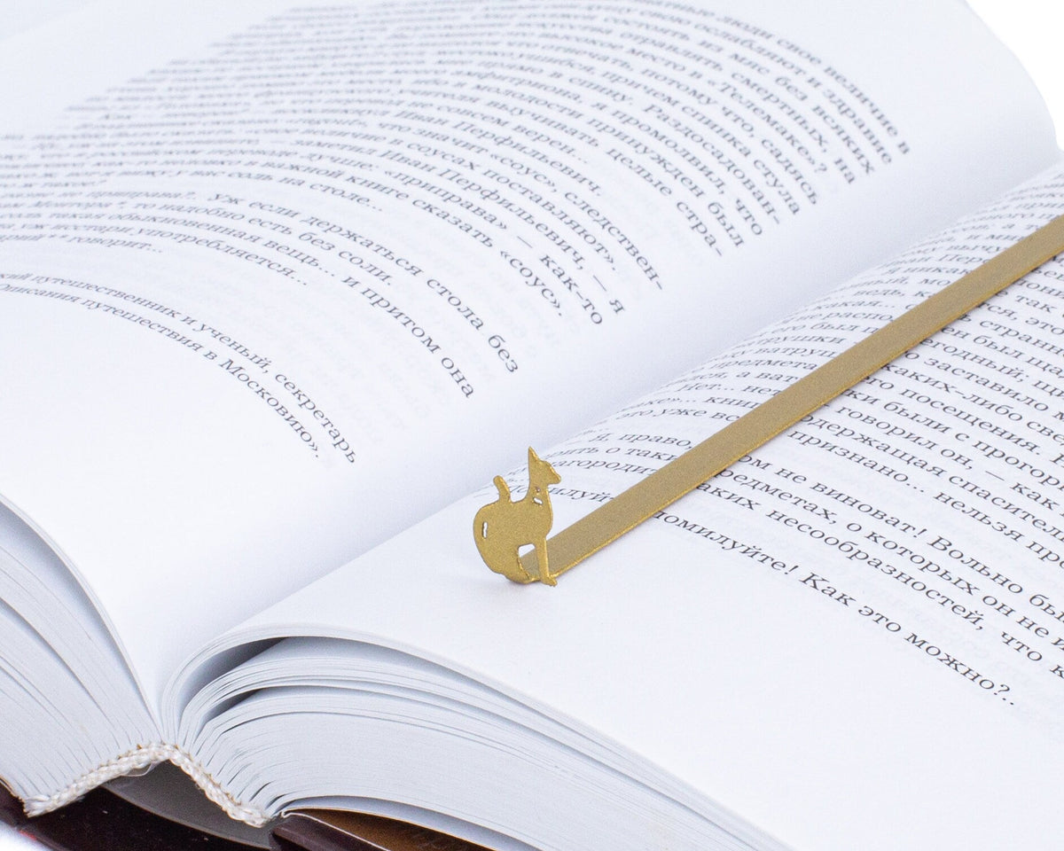 Egyptian Cat metal bookmark in gold resting on the pages of an open book