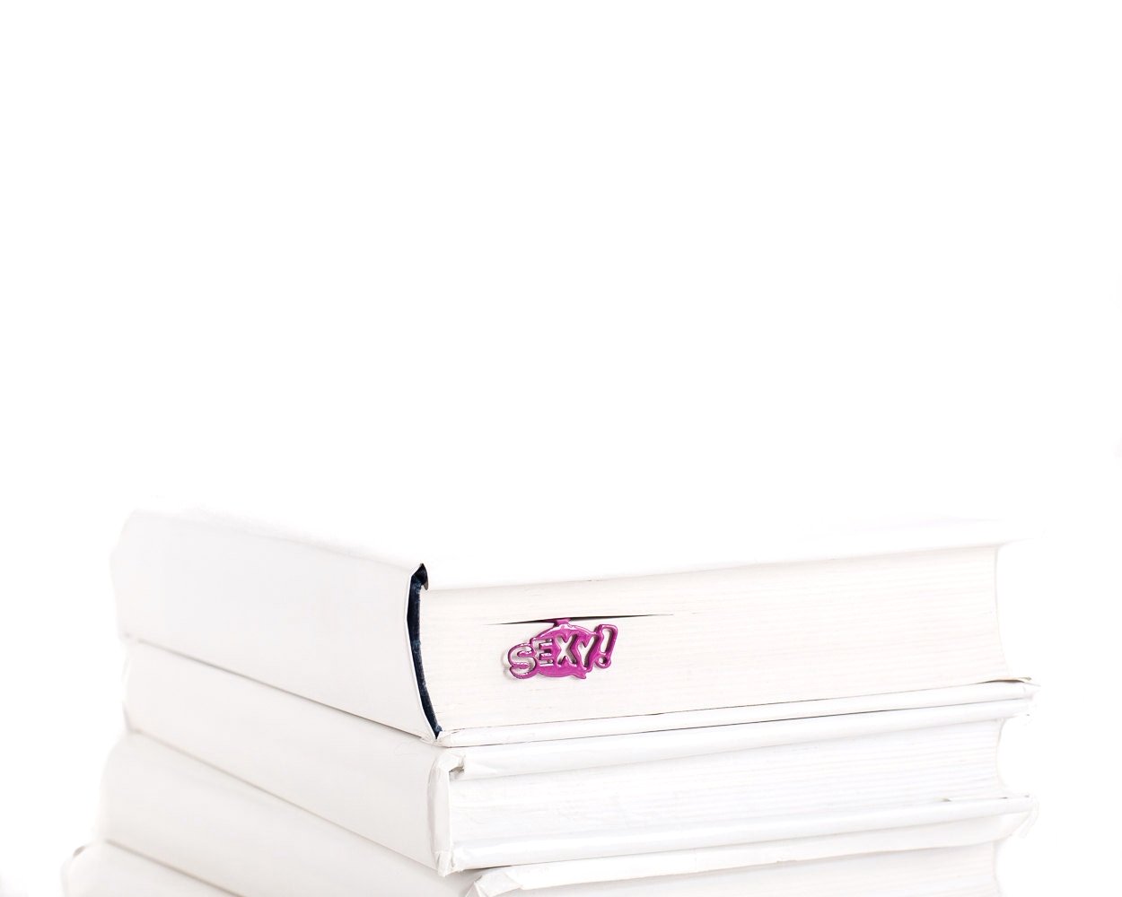 Burgundy metal Sexy Smart bookmark in a book — comic-bubble word visible above the pages