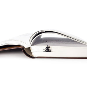Skier in High Hat metal bookmark resting on the pages of an open book