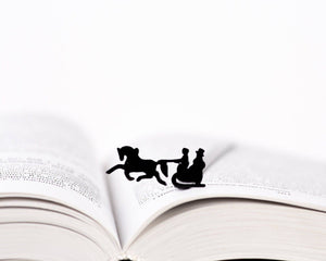 Winter Sleigh metal bookmark resting on the pages of an open book