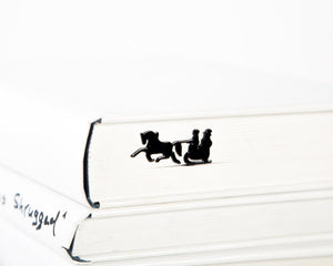 Winter Sleigh metal bookmark in a closed book, only its top showing above the pages