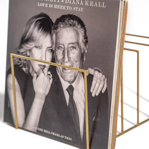 Close-up of a sleek gold metal vinyl record holder displaying a black-and-white Tony Bennett & Diana Krall album cover. The minimalist design adds a touch of elegance to the display.