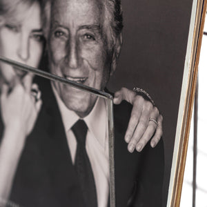 Close-up of a vinyl record cover featuring Tony Bennett and Diana Krall, placed in a silver metal record holder. The image highlights the detailed wire construction and brushed texture of the stand against the monochrome album artwork.