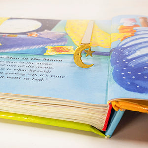 Gold crescent moon and star bookmark clipped to the page of a colorful children’s bedtime book open to a poem about the man in the moon