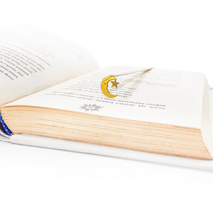 Gold crescent moon and star bookmark resting on the pages of an open book with aged paper and Russian text, set against a white background