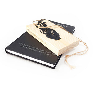 Black metal golf bag bookmark displayed on a light wooden block engraved “Reading is good for you,” tied with natural twine and placed on a closed book, showing gift-ready packaging.
