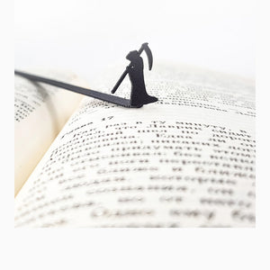 Grim Reaper metal bookmark resting on the pages of an open book