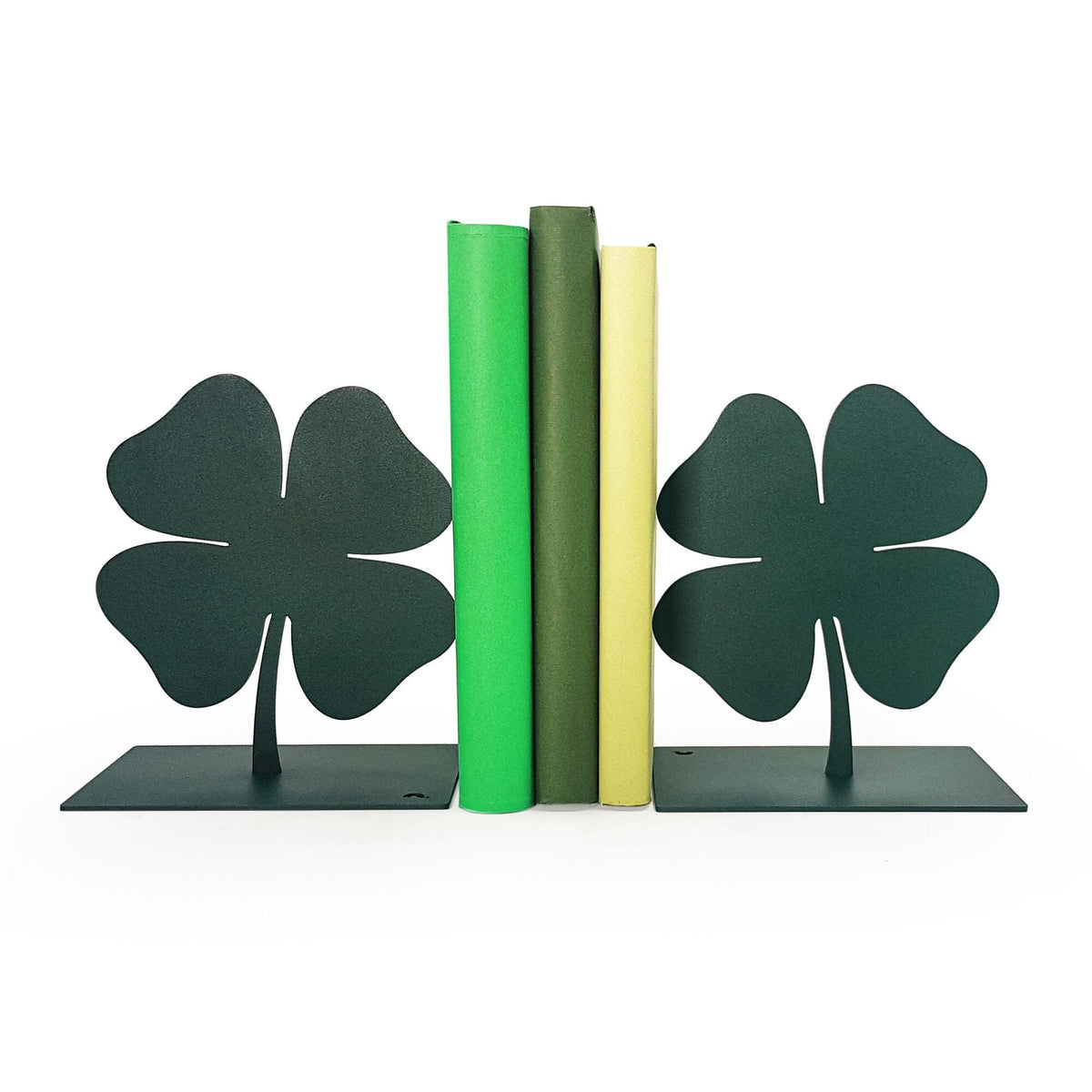 Dark green metal bookends shaped like four-leaf clovers, holding three green and yellow books, minimalist and sturdy design. Design and made by Atelier Article in Ukraine. Not mass-produced.