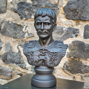Black bust of a Roman emperor Julius Caesar by the stone wall