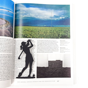 Black metal lady golf player bookmark placed on an open art book page, contrasting with the landscape photography beneath