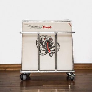 Front view of a white metal vinyl record crate with wheels, holding a Whitesnake “Trouble” album, on a wooden floor.
