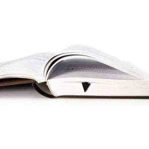 Minimalist Triangle metal bookmark resting on the pages of an open book