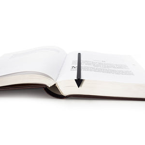 Minimalist Triangle metal bookmark lying across the pages of an open book