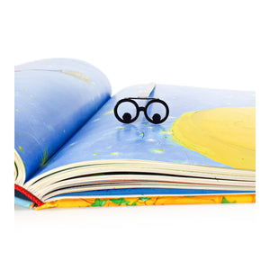 Reading Eyes metal bookmark marking a page in an illustrated book