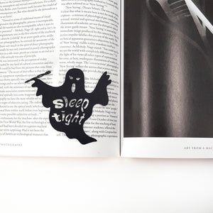 Ghost-shaped paper cutout with 'Sleep tight' text on an open book