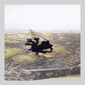 Three Headed Dragon metal bookmark on a coloured background
