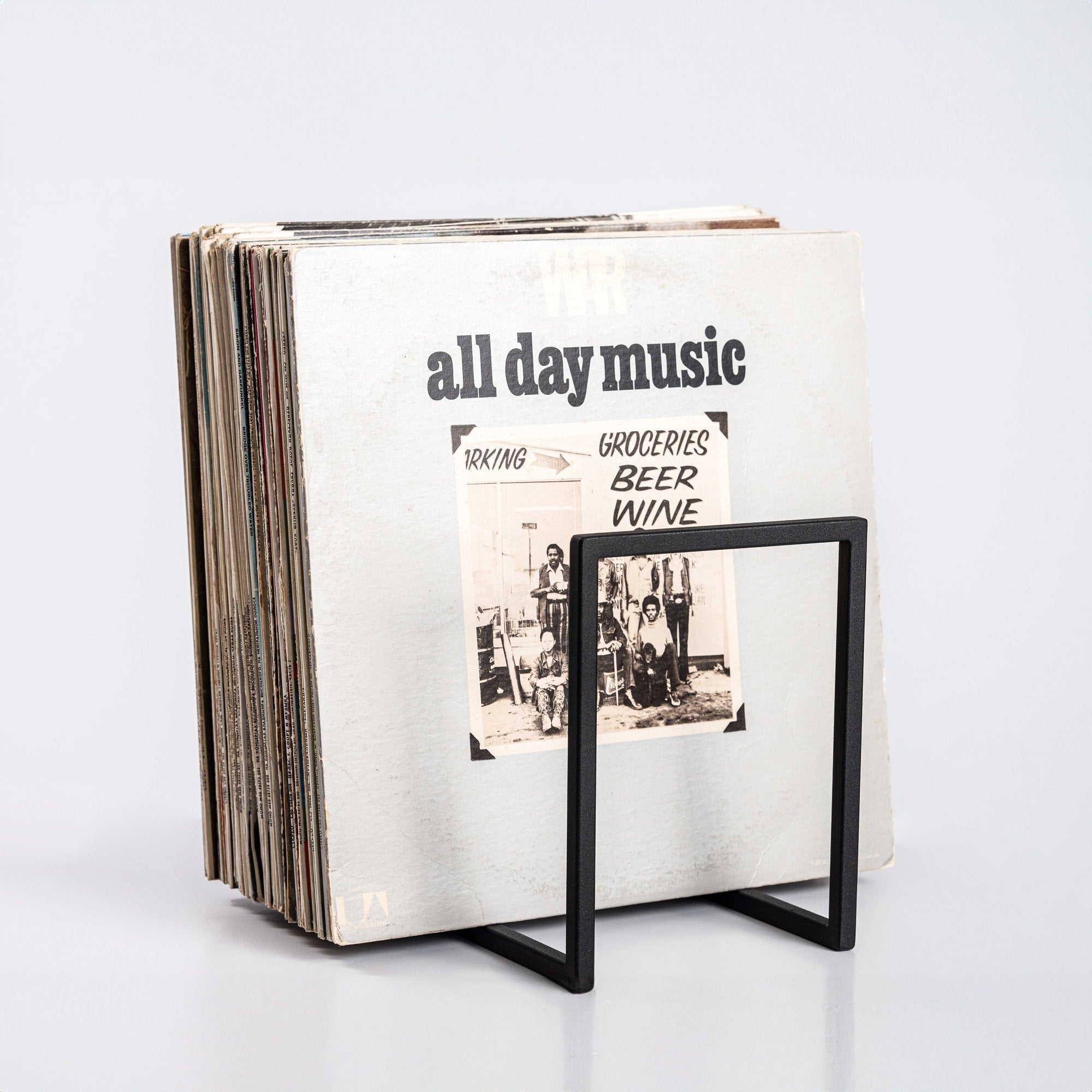 Minimalist metal vinyl record stand holding a large collection of LPs, displayed on white background.