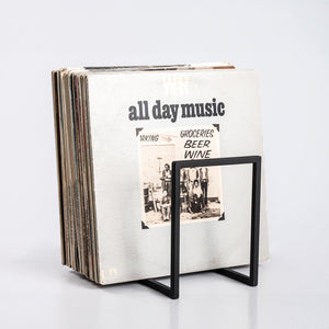 Minimalist metal vinyl record stand holding a large collection of LPs, displayed on white background.