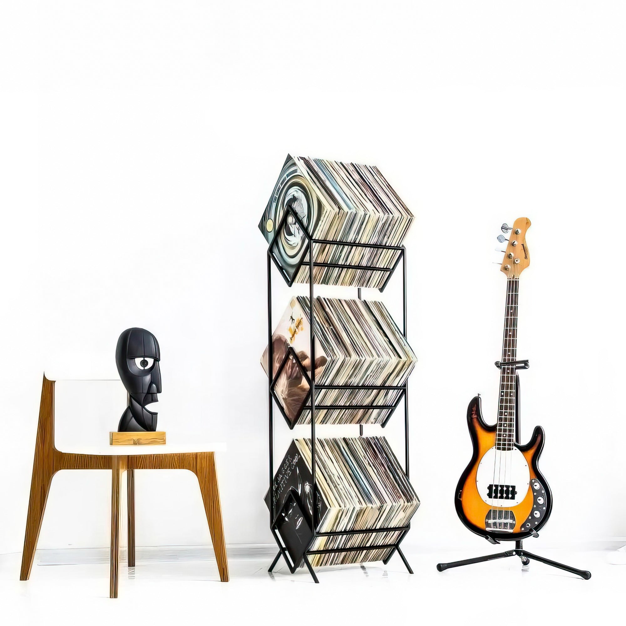 three-tier vinyl record stand by a guitar and a char with black head sculpture Division bell.