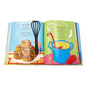 A black whisk-shaped metal bookmark lies on the left page of an open children’s book featuring the rhyme “Hot Cross Buns” with illustrated buns and a child’s hand.