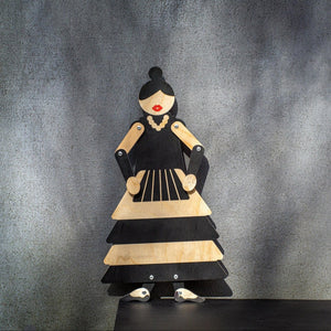Wooden flamenco puppet displayed on black shelf against grey wall, arms posed at sides