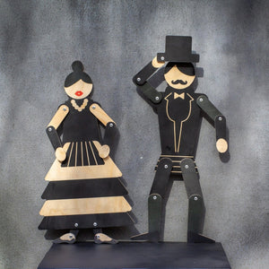 Wooden flamenco puppet displayed alongside gentleman puppet companion on dark shelf