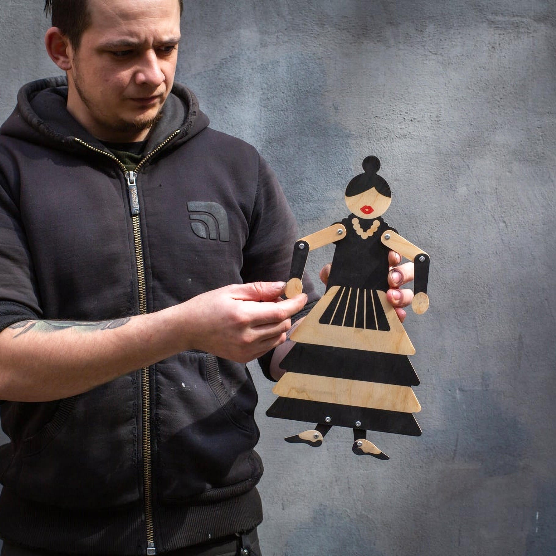 Craftsman posing wooden flamenco puppet by hand, showing scale and movable joints