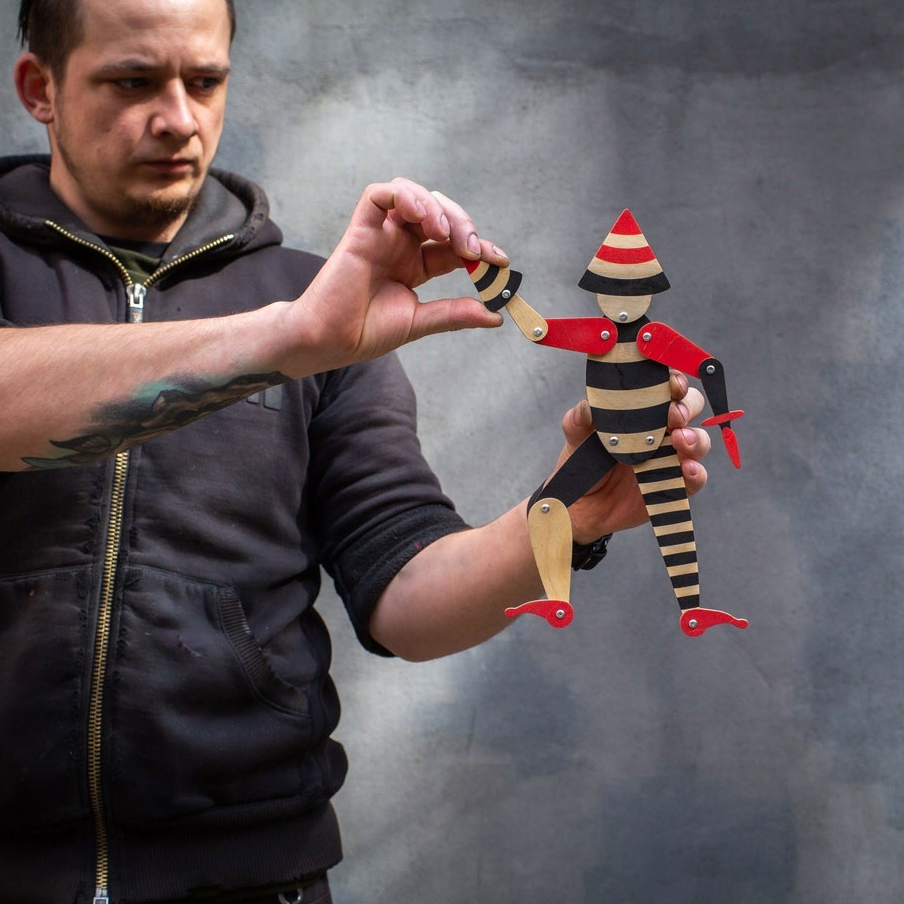 Man holding handmade articulated plywood acrobat puppet demonstrating movable joints