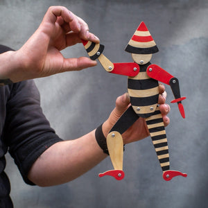 Hands holding handmade articulated plywood acrobat puppet showing movable arm joint