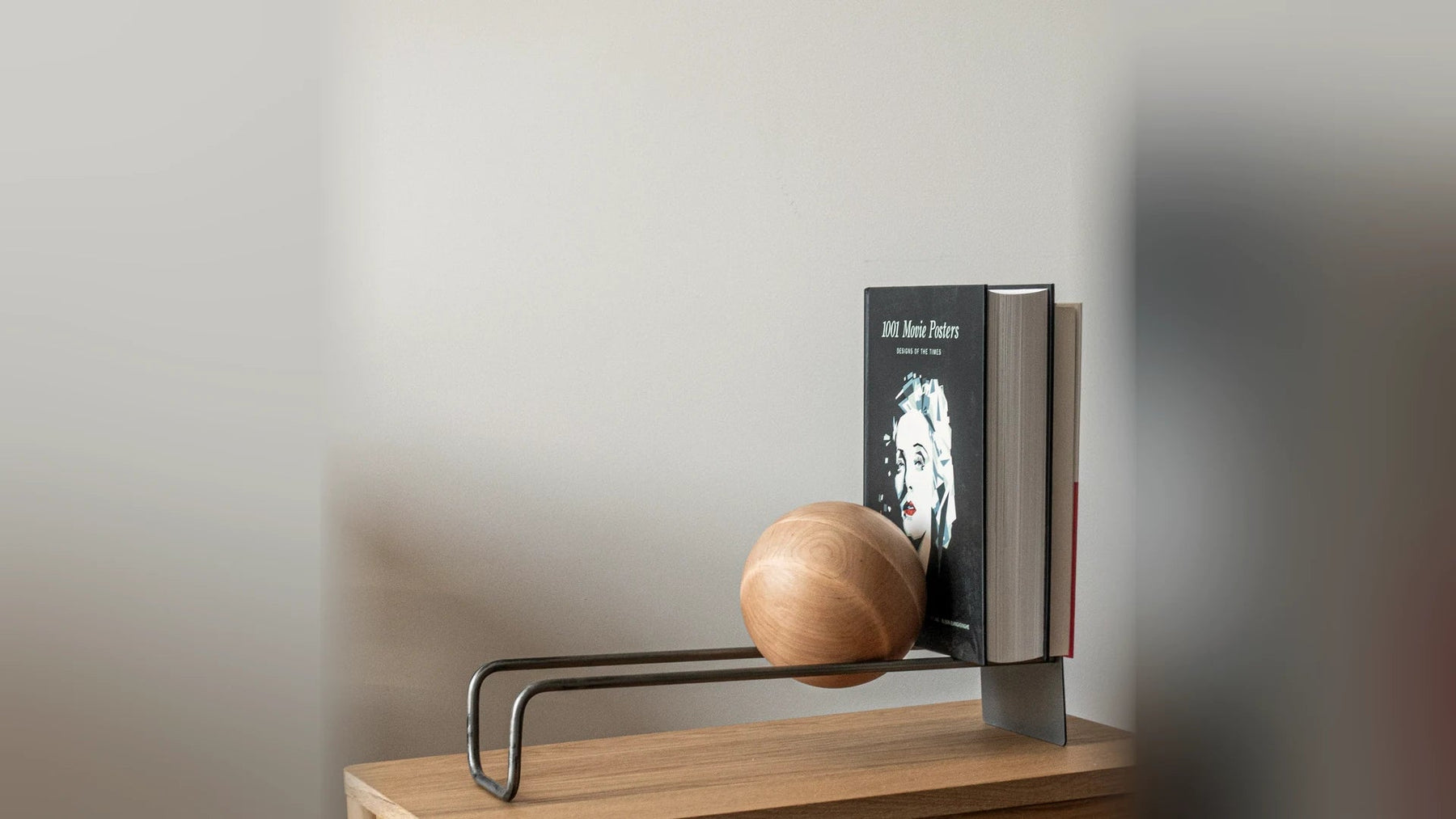 Hardcover music books propped upright by a steel stand with a wooden ball.
