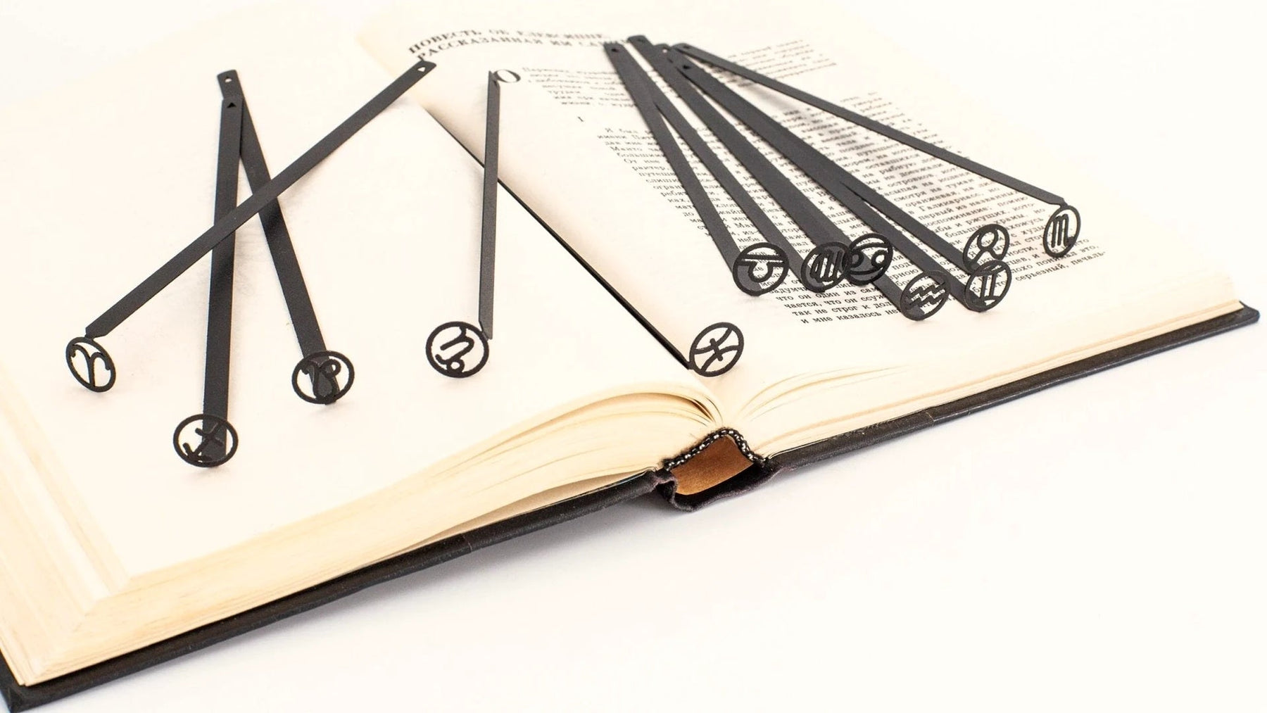 Set of slim steel bookmarks laid across the pages of an open book.