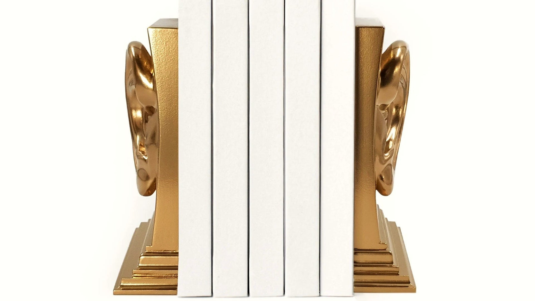 Gold anatomical ear bookends holding a row of white books.
