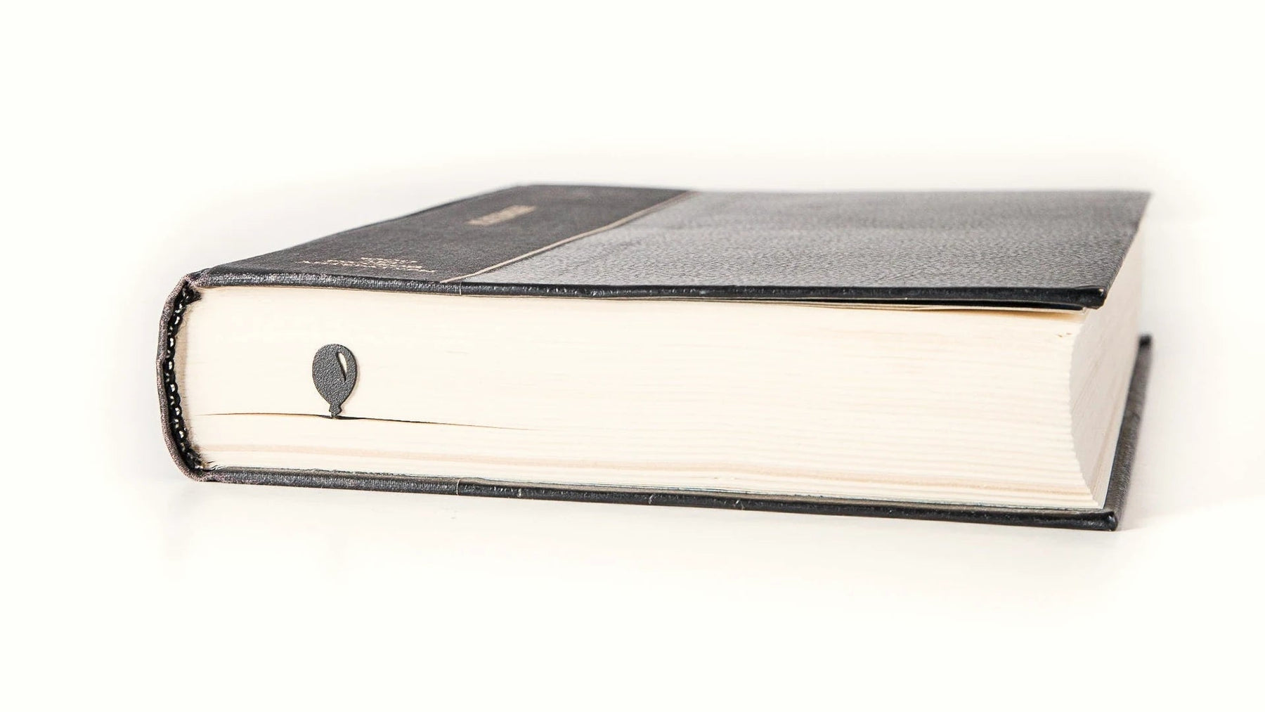 Slim steel bookmark marking a page in a closed hardcover book.
