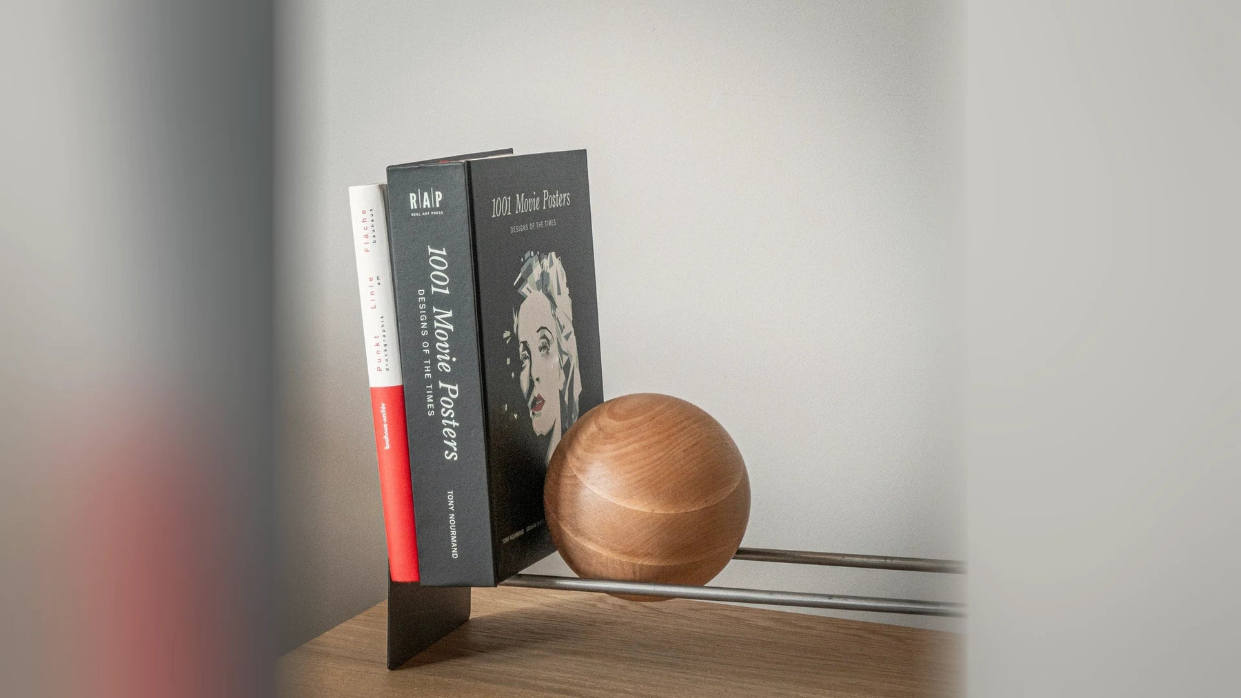 Books and LP records held upright by a steel stand with a wooden ball.