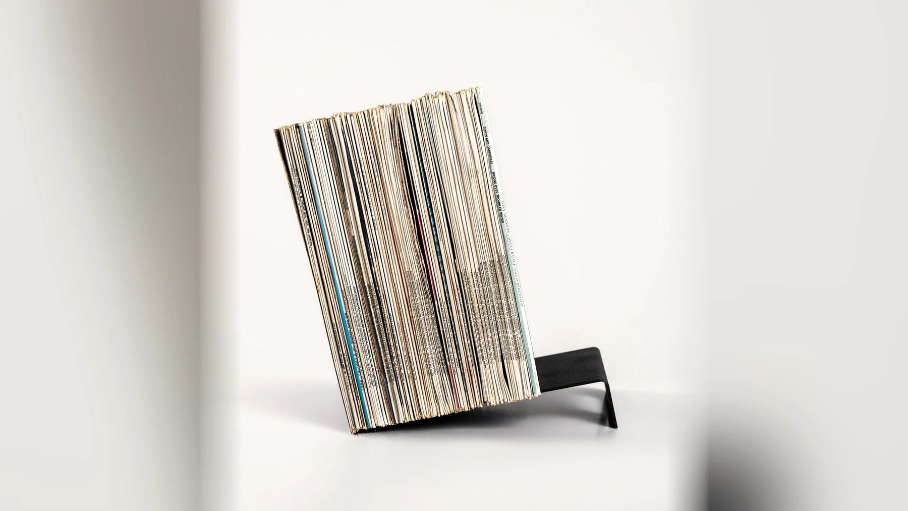 A stack of LP records leaning at an angle on a low steel support.