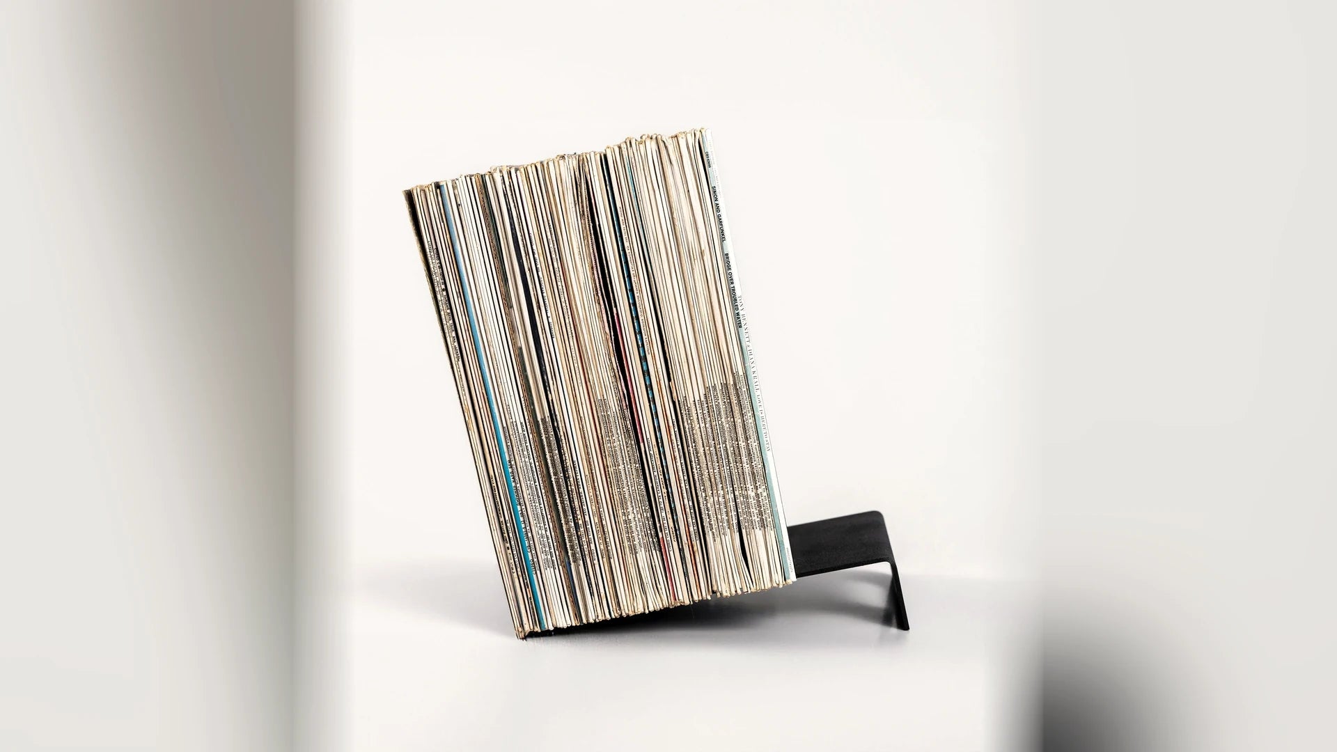 A stack of LP records leaning at an angle on a low steel support.