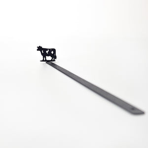 Full product shot — 17 cm laser-cut black steel cow bookmark on white background, diagonal view
