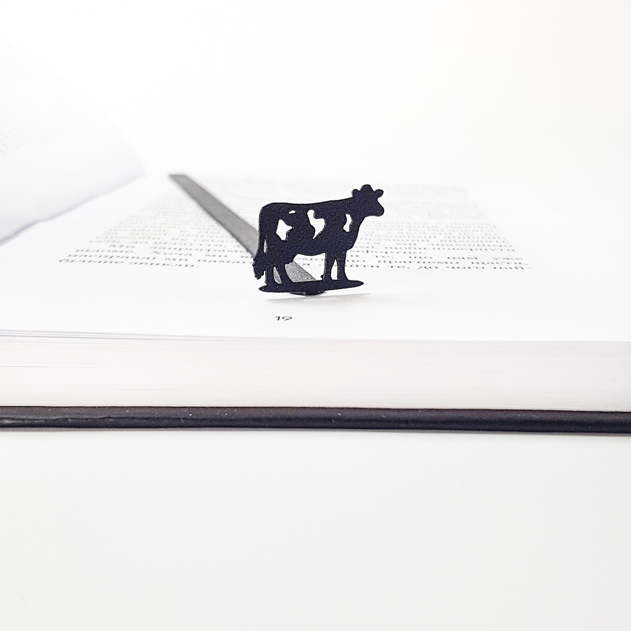 Metal cow bookmark detail shot showing cut-out spots on cow silhouette, matte black finish