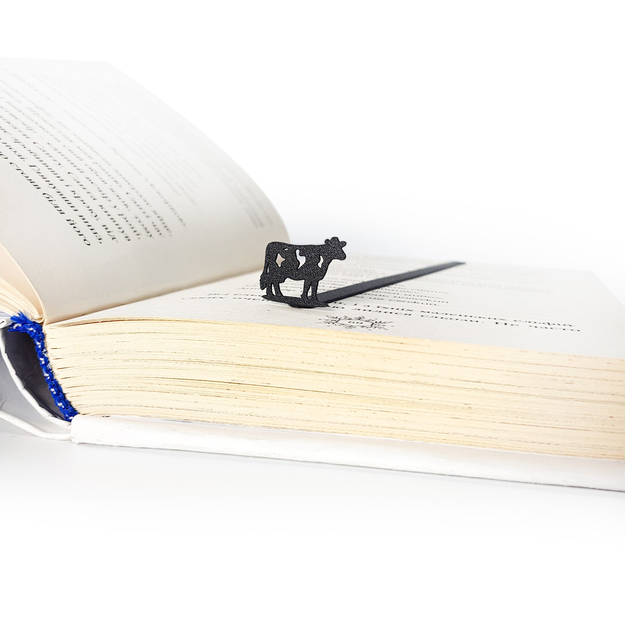 Metal cow bookmark macro detail showing laser-cut steel edges and matte black surface