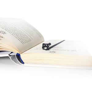 Steel cow bookmark in open book lifestyle shot, warm natural light setting