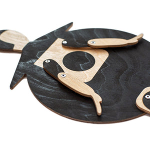 Bauhaus Beetle puppet lying flat on white background — detail of black-stained plywood body and jointed wooden arms