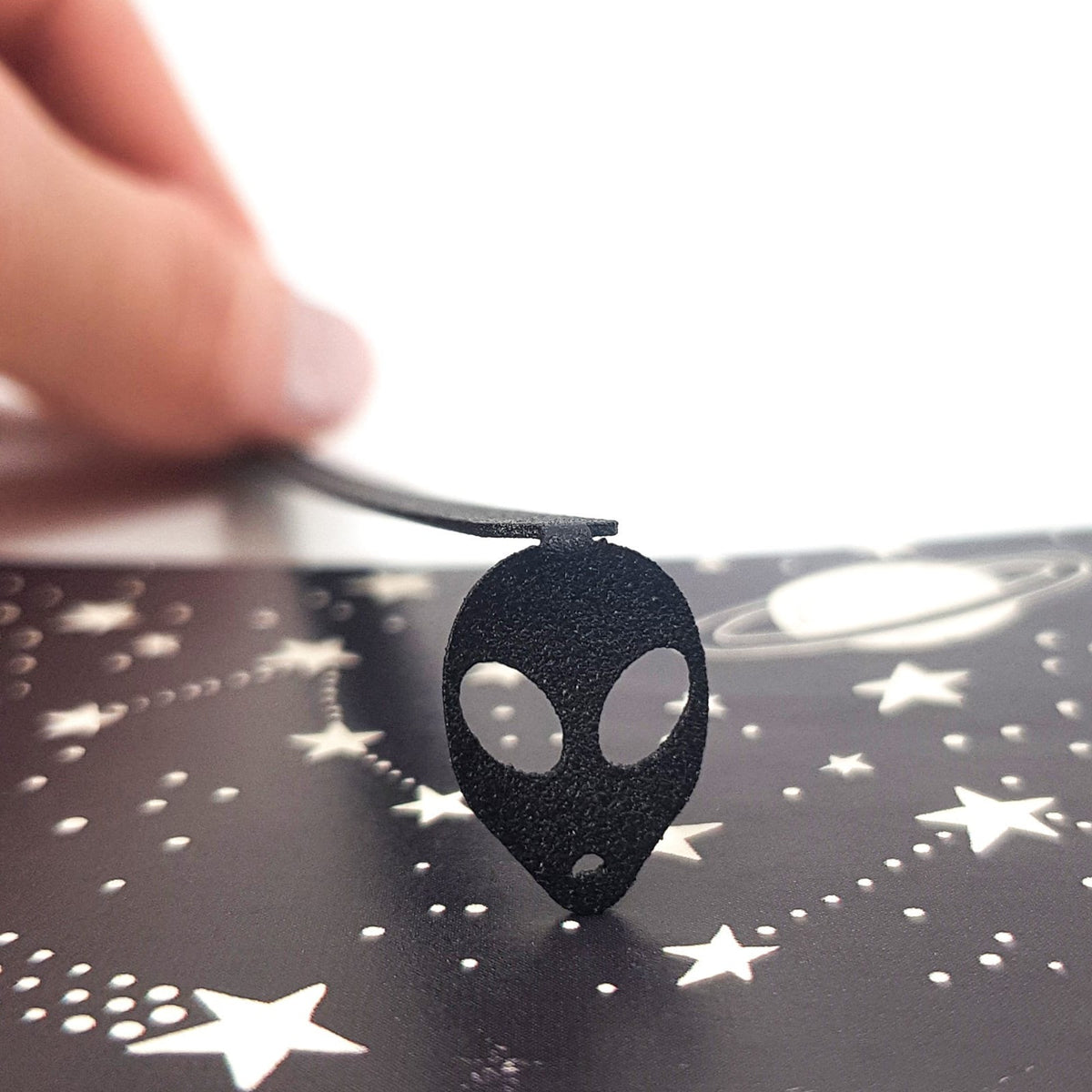 Alien Head metal bookmark on a coloured background