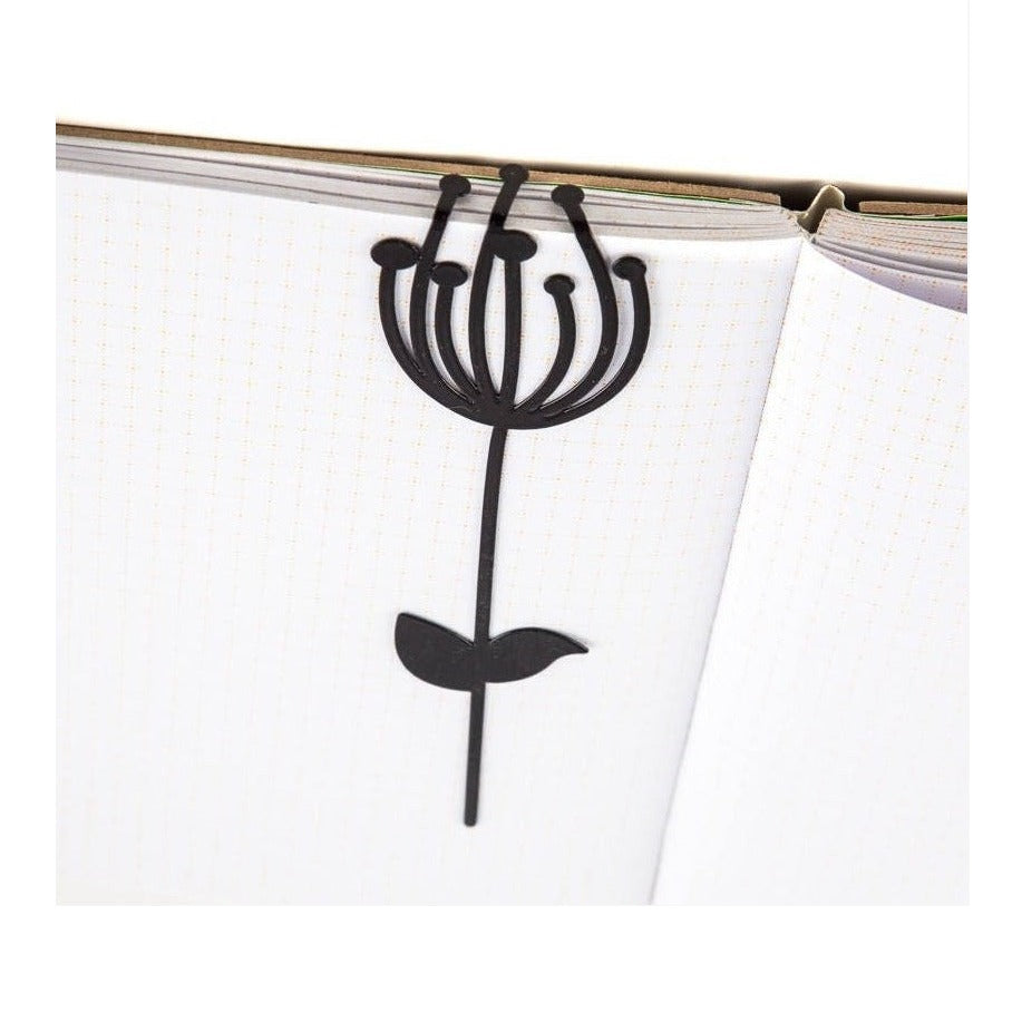 Anethum metal bookmark resting on the pages of an open book