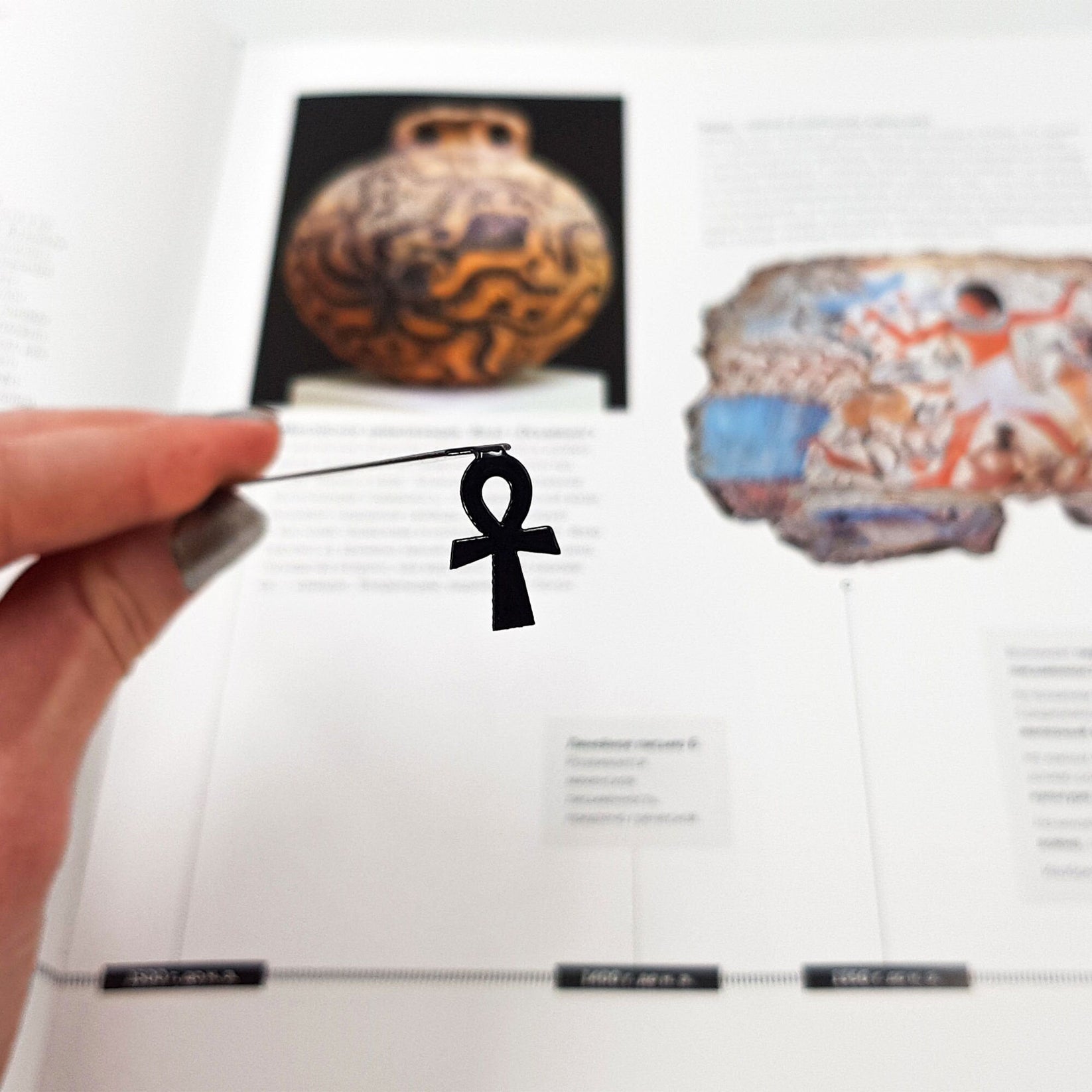 Ankh metal bookmark marking a page in an illustrated book