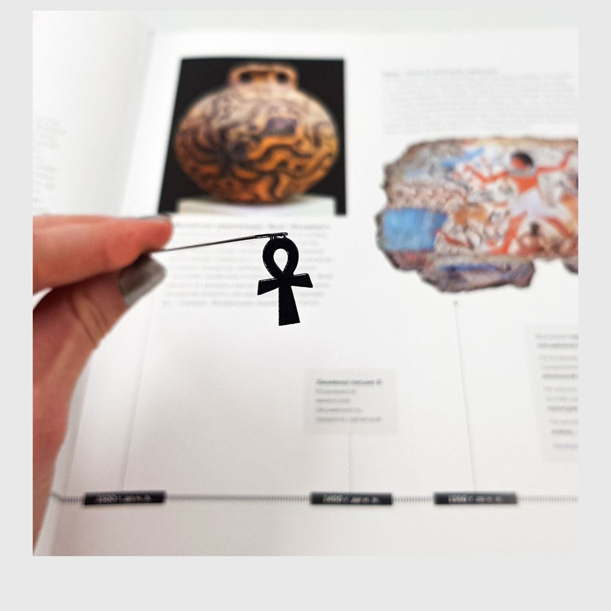 Ankh metal bookmark marking a page in an illustrated book