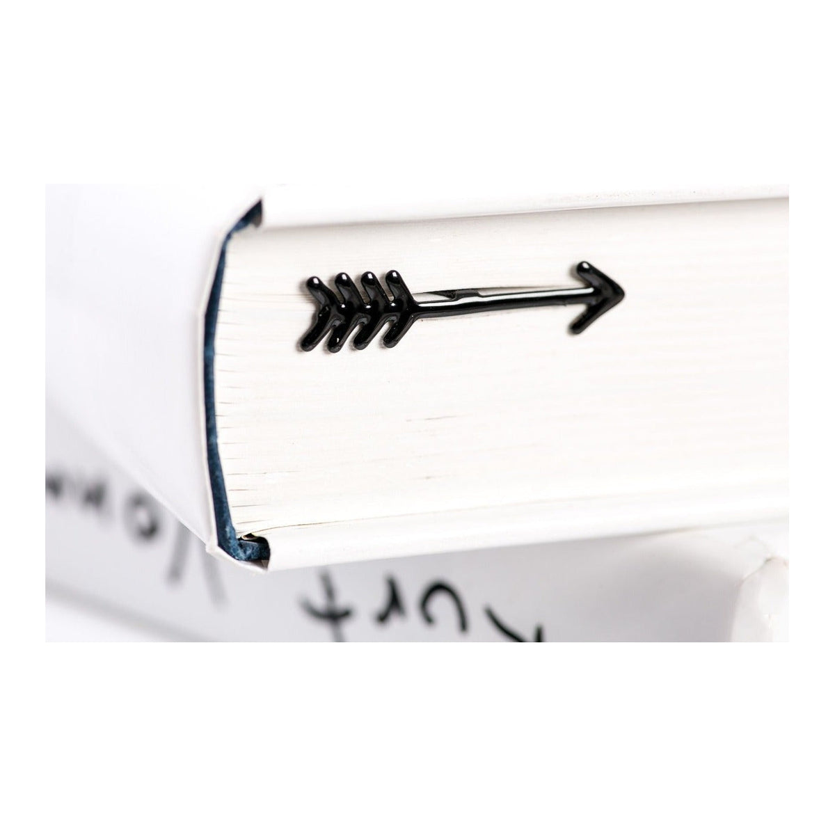 Arrow metal bookmark in a closed book, only its top showing above the pages