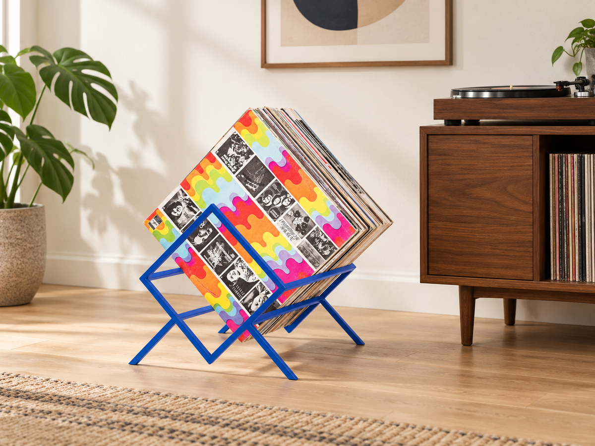 Blue Atelier Article 1Romb single-tier vinyl record stand with diagonally arranged LPs beside a walnut turntable cabinet in a sunlit room.