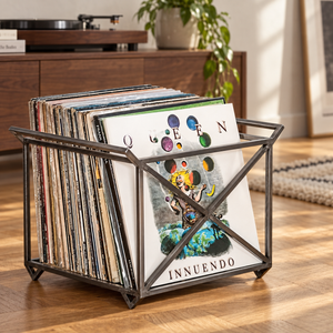 Atelier Article steel vinyl record crate with side handles and X-shaped braces, holding Queen Innuendo and other LPs beside a turntable.